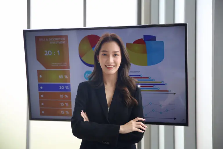 A professional businesswoman presenting analytics on a digital signage screen, showcasing investment data and interactive visuals for an executive meeting.
